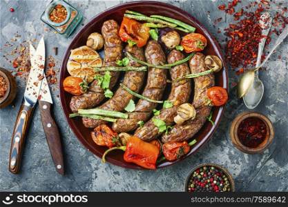 Grilled sausage with mushrooms and tomatoes on plate. Tasty grilled sausages