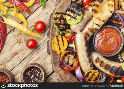 Grilled sausages and vegetables with sauce ketchup on a wooden table.Autumn food. Fried sausages with sauces