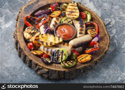 Grilled sausages fried with pear and vegetables. Autumn food.. Fried sausages with sauces