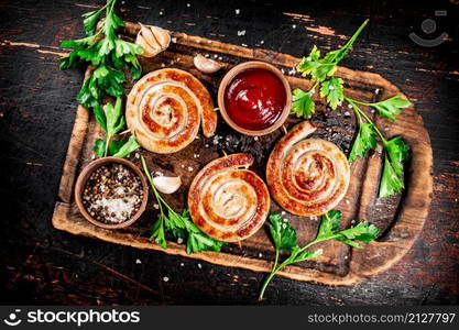 Grilled sausages with parsley and tomato sauce. Against a dark background. High quality photo. Grilled sausages with parsley and tomato sauce.