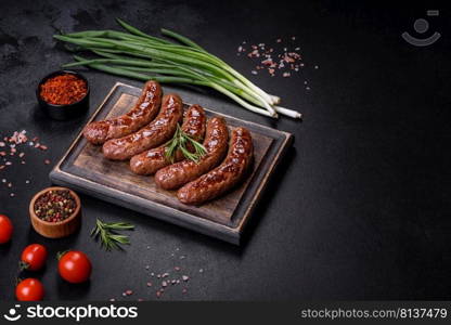 Grilled sausages with spices and herbs. Top view flat lay. With copy space. Grilled sausages with ingredients on a cutting board on a stone background