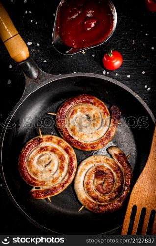 Grilled sausages with tomato sauce. On a black background. High quality photo. Grilled sausages with tomato sauce.