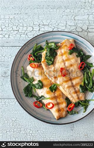 Grilled sea bream fish fillet with spinach and chili pepper