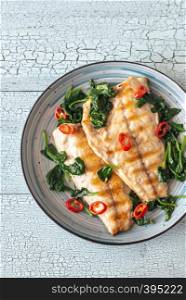 Grilled sea bream fish fillet with spinach and chili pepper