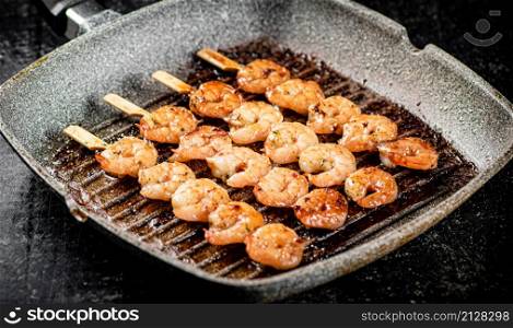 Grilled shrimp in a frying pan. On a rustic background. High quality photo. Grilled shrimp in a frying pan.