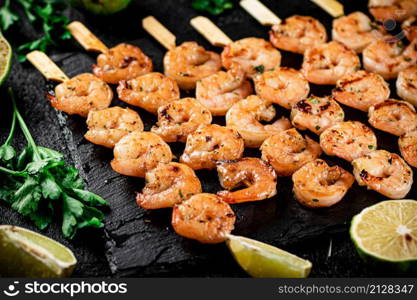 Grilled shrimp on a stone board with parsley and lime. On a black background. High quality photo. Grilled shrimp on a stone board with parsley and lime.