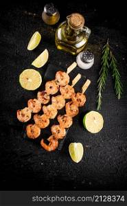 Grilled shrimp on a stone board with pieces of lime. On a black background. High quality photo. Grilled shrimp on a stone board with pieces of lime.