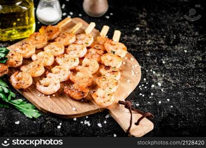 Grilled shrimp on a wooden cutting board. On a black background. High quality photo. Grilled shrimp on a wooden cutting board.