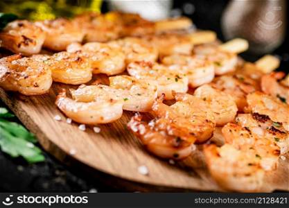 Grilled shrimp on a wooden cutting board. On a black background. High quality photo. Grilled shrimp on a wooden cutting board.