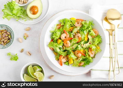 Grilled shrimp salad with avocado, mango, lettuce and pistachios, dressed with lime. Healthy food. Ketogenic diet. Top view.