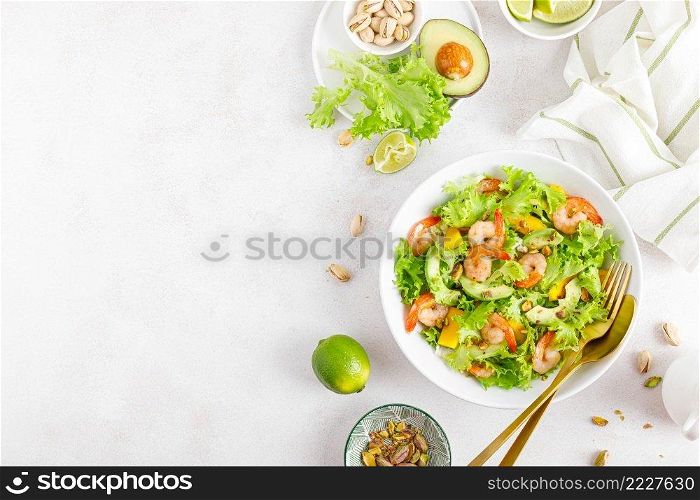 Grilled shrimp salad with avocado, mango, lettuce and pistachios, dressed with lime. Healthy food. Ketogenic diet. Top view.