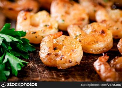 Grilled shrimp with parsley on a wooden background. High quality photo. Grilled shrimp with parsley on a wooden background.