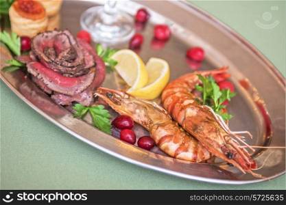Grilled shrimps and beef meat on a plate