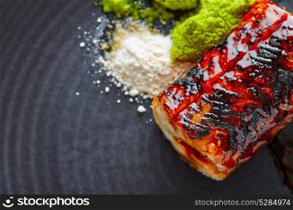 Grilled smoked eel with green apple and citrus on black plate