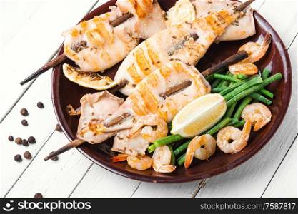 Grilled squid or calamari on skewer.Barbecue squids on a plate.. Grilled squid on a skewer