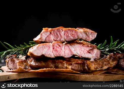 Grilled steak cut into pieces. On a black background. High quality photo. Grilled steak cut into pieces.