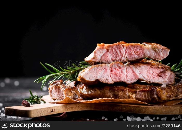 Grilled steak cut into pieces. On a black background. High quality photo. Grilled steak cut into pieces.