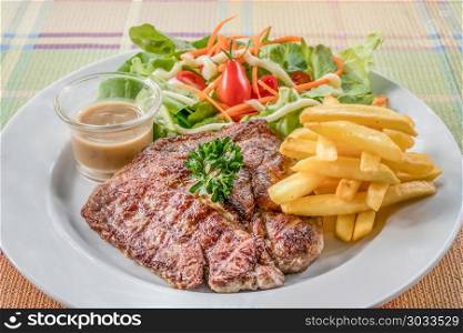 Grilled steak on dish. Grilled steak with french fries and fresh vegetables on white plate