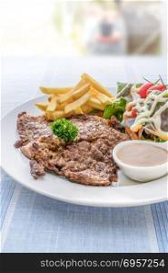 Grilled steak on dish. Grilled steak with french fries and fresh vegetables on white plate