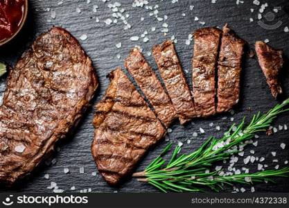 Grilled steak with a sprig of rosemary. On a black background. High quality photo. Grilled steak with a sprig of rosemary.
