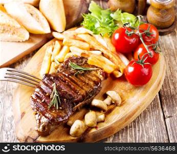 grilled steak with vegetables on wooden plate