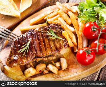 grilled steak with vegetables on wooden plate