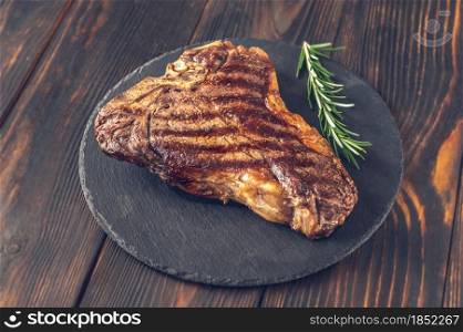 Grilled T-bone steak with fresh rosemary on the stone board