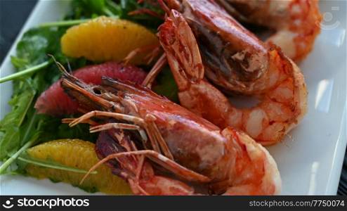 Grilled tiger prawns or shrimps with orange grapefruit and greens on a plate. Grilled tiger prawns or shrimps