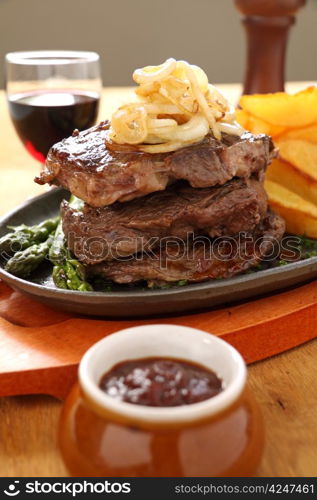 Grilled triple decker rib fillet steak with fried onion and chips ready to serve.