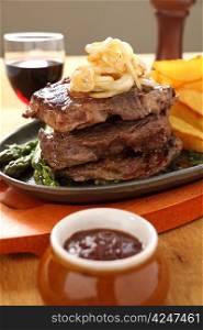 Grilled triple decker rib fillet steak with fried onion and chips ready to serve.
