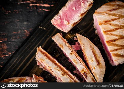 Grilled tuna on a cutting board. Against a dark background. High quality photo. Grilled tuna on a cutting board.