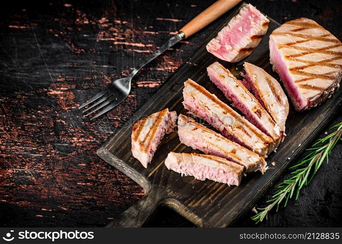 Grilled tuna on a cutting board. Against a dark background. High quality photo. Grilled tuna on a cutting board.