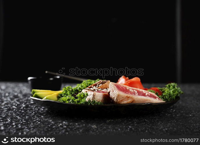 Grilled Tuna Steak and Avocado on a black plate