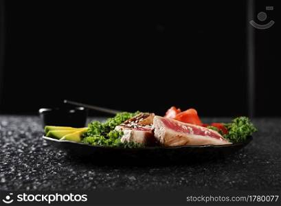 Grilled Tuna Steak and Avocado on a black plate