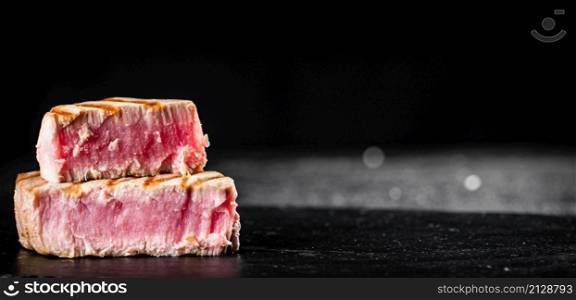Grilled tuna steak on the table. On a black background. High quality photo. Grilled tuna steak on the table.