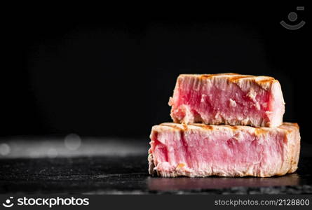 Grilled tuna steak on the table. On a black background. High quality photo. Grilled tuna steak on the table.