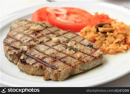 Grilled tuna steak with limpets rice and tomatoes.