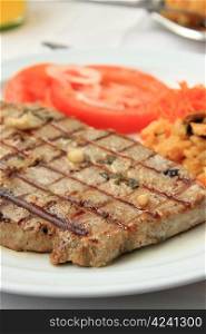 Grilled tuna steak with limpets rice and tomatoes.