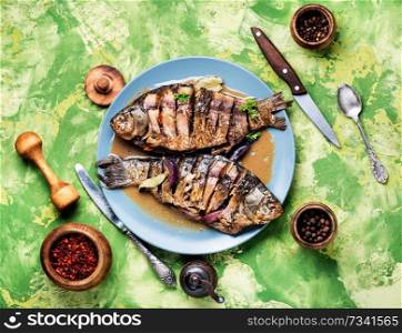 Grilled whole fish with citrus, and vegetable on rustic table. Tasty baked fish on plate