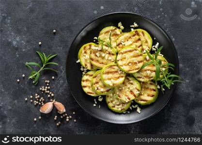Grilled zucchini, courgette with garlic and rosemary on plate, top view