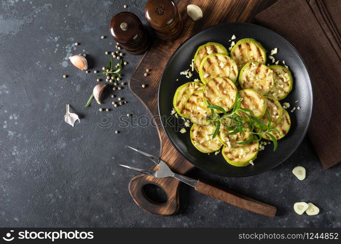 Grilled zucchini, courgette with garlic and rosemary on plate, top view