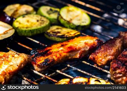 Grilling meat rolls called mici or mititei with vegetables on char barbecue. Charcoal grill with burning fire