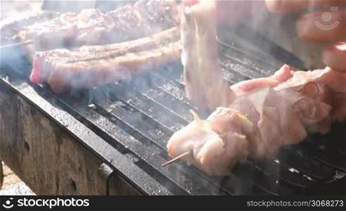 Grilling pork meat and sticks with bacon rolled meat on barbecue