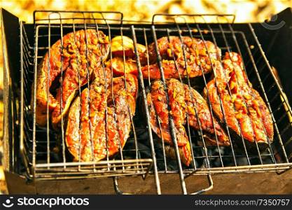 grilling salmon steak with ginger marinade in wire rack over barbecue. Top view grilled salmon on flaming braai. 