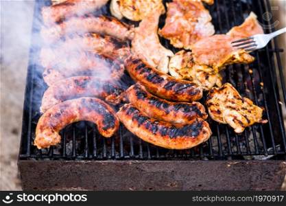 Grilling sausages and pork chops on barbecue grill. BBQ in the garden