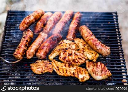 Grilling sausages and pork chops on barbecue grill. BBQ in the garden