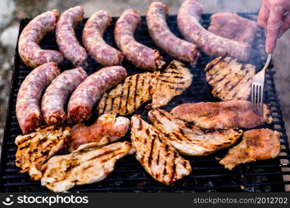 Grilling sausages and pork chops on barbecue grill. BBQ in the garden