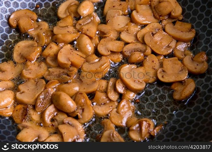 Grinded mushrooms champignon roasting in pan.