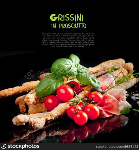 Grissini with prosciutto crudo and vegetables on black