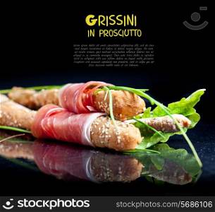 Grissini with prosciutto crudo and vegetables on black
